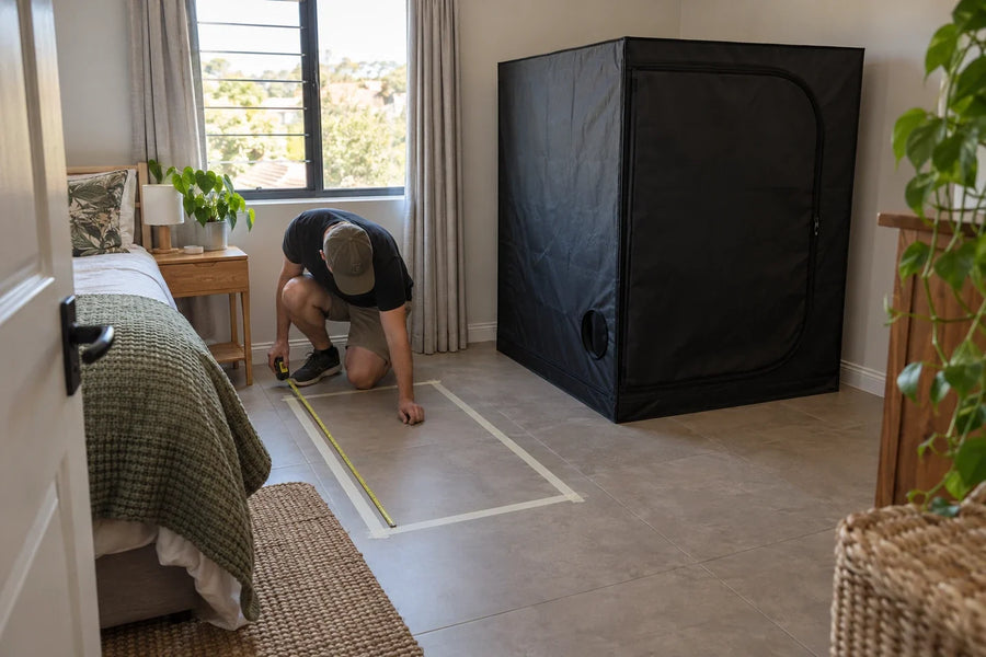 A long rectangular floor outline compared with a 90cm square grow tent in a furnished spare room